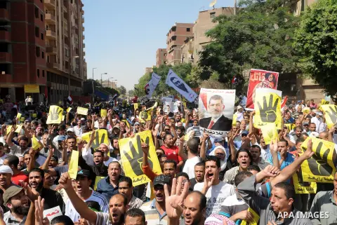 Egyptians supporters of ousted president Morsi hold posters depicting him and others depicting a hand in a sign of the number four during a Friday protest called for by the Muslim Brotherhood in Helwan, Egypt, 23 August...