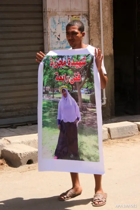 An Egyptian supporter of ousted president Morsi holds a poster of a killed woman by Egyptian military forces during a Friday protest called for by the Muslim Brotherhood outside al-Aziz Bellah Mosque, Egypt, 23 August 20...