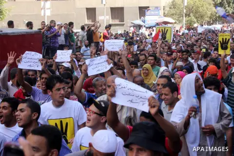 Egyptians supporters of ousted president Morsi hold posters depicting him and others depicting a hand in a sign of the number four during a Friday protest called for by the Muslim Brotherhood outside al-Aziz Bellah Mosqu...