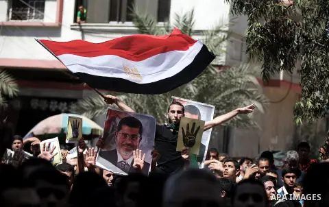 Palestinians hold Egyptian national flags, posters of ousted Egyptian President Mohamed Morsi and logos of four fingers, during a demonstration to support Morsi and denounce Syria's President Bashar al-Assad, in Al-Nusir...