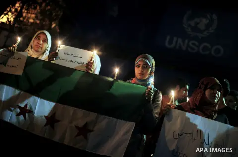 Young Palestinian women hold syrian revolution flags and lit candles during a protest against Syria's President Bashar al-Assad in front of the U.N. headquarters in Gaza City August 23, 2013. U.N. Secretary-General Ban K...