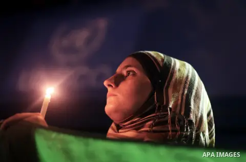 A Young Palestinian woman holds syrian revolution flag and a lit candle during a protest against Syria's President Bashar al-Assad in front of the U.N. headquarters in Gaza City August 23, 2013. U.N. Secretary-General Ba...
