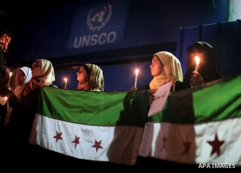 Young Palestinian women hold syrian revolution flags and lit candles during a protest against Syria's President Bashar al-Assad in front of the U.N. headquarters in Gaza City August 23, 2013. U.N. Secretary-General Ban K...