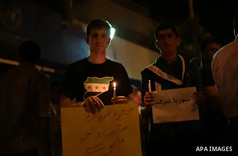 Palestinians hold syrian revolution flags and lit candles during a protest against Syria's President Bashar al-Assad in front of the U.N. headquarters in Gaza City August 23, 2013. U.N. Secretary-General Ban Ki-moon said...
