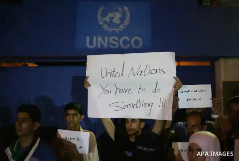 Palestinians hold placards during a protest against Syria's President Bashar al-Assad in front of the U.N. headquarters in Gaza City August 23, 2013. U.N. Secretary-General Ban Ki-moon said on Friday he intends to conduc...