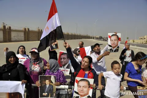 Supporters of former Egyptian president Hosni Mubarak wave his portrait outside the Police Academy ahead of his trial on August, 25 2013 in Cairo. An Egyptian court adjourned the murder and corruption retrial of former s...