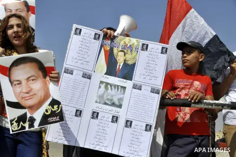 Supporters of former Egyptian president Hosni Mubarak wave his portrait outside the Police Academy ahead of his trial on August, 25 2013 in Cairo. An Egyptian court adjourned the murder and corruption retrial of former s...