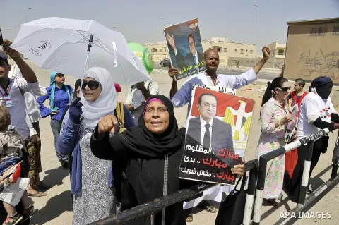 Supporters of former Egyptian president Hosni Mubarak wave his portrait outside the Police Academy ahead of his trial on August, 25 2013 in Cairo. An Egyptian court adjourned the murder and corruption retrial of former s...