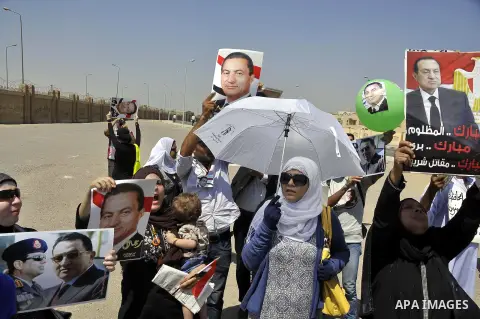 Supporters of former Egyptian president Hosni Mubarak wave his portrait outside the Police Academy ahead of his trial on August, 25 2013 in Cairo. An Egyptian court adjourned the murder and corruption retrial of former s...