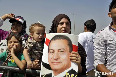 Supporters of former Egyptian president Hosni Mubarak wave his portrait outside the Police Academy ahead of his trial on August, 25 2013 in Cairo. An Egyptian court adjourned the murder and corruption retrial of former s...