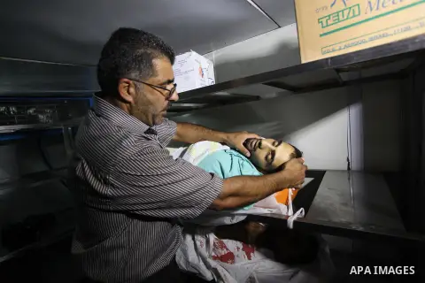 A man shows the body of a Palestinian man who was killed during clashes with Israeli security forces in Qalandia refugee camp, at a hospital in the West Bank city of Ramallah on August 26, 2013. An Israeli police spokesw...