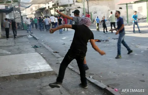 A Palestinian protester throws stones towards Israeli soldiers (unseen) during clashes following a protest against Israeli settlements on August 27,2013 in the city center of the West Bank town of Hebron. Israeli-Palesti...