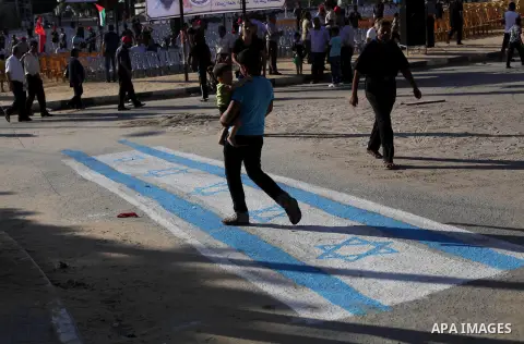 A Palestinian supporter of Popular Front for the Liberation of Palestine (PFLP) walks on an Israeli flag during a rally marking the 12th anniversary of the killing of Abu Ali Mustafa, leader of (PLFP), in Gaza City Augus...