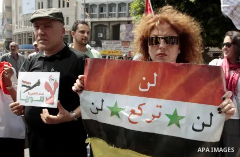 Palestinian protesters hold placards and Syrian flags during a demonstration against the United States' involvement in Syria, in the West Bank City of Nablus,Aug. 29, 2013. U.S. President Barack Obama on Wednesday declar...