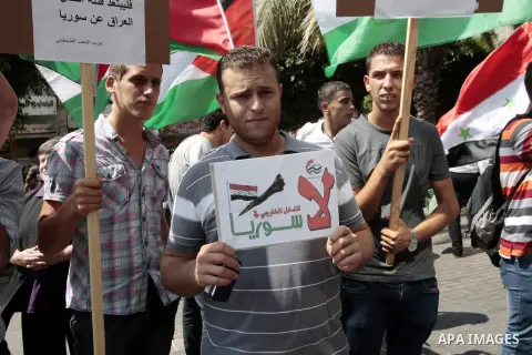 Palestinian protesters hold placards and Syrian flags during a demonstration against the United States' involvement in Syria, in the West Bank City of Nablus,Aug. 29, 2013. U.S. President Barack Obama on Wednesday declar...