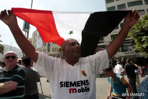 A Palestinian man holds a Syrian flag during a demonstration against the United States' involvement in Syria, in the West Bank City of Nablus,Aug. 29, 2013. U.S. President Barack Obama on Wednesday declared unequivocally...