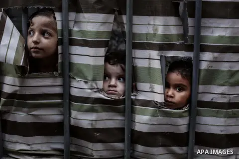 Palestinian girls look behind a curtain at her family's home at al-Shati refugee camp, in Gaza City on Aug 29, 2013. Photo by Ashraf Amra