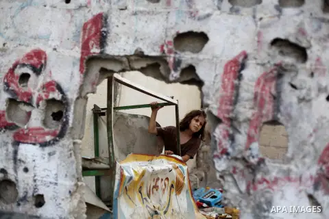 A Palestinian girl plays next to her family's home at al-Shati refugee camp, in Gaza City on Aug 29, 2013. Photo by Ashraf Amra