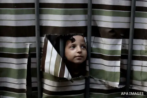 A Palestinian girl looks behind a curtain at her family's home at al-Shati refugee camp, in Gaza City on Aug 29, 2013. Photo by Ashraf Amra
