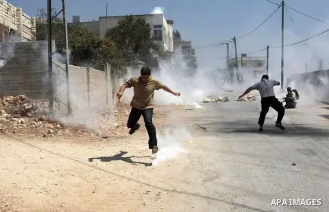 Palestinian protesters kick back tear gas canisters fired by Israeli security forces during clashes following a protest against the expropriation of Palestinian land by Israel in the village of Kfar Qaddum, near Nablus i...