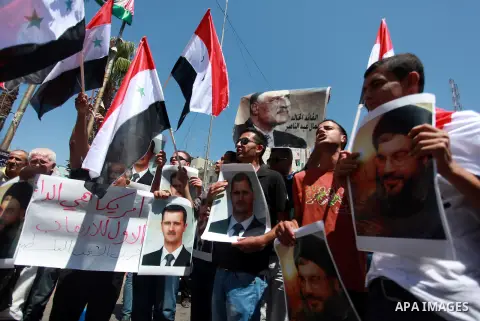 Palestinian protesters hold a flags and poster of Syria's President Bashar al-Assad during a demonstration against potential strikes on the Syrian government, in the West Bank City of Ramallah August 31, 2013. Photo by I...