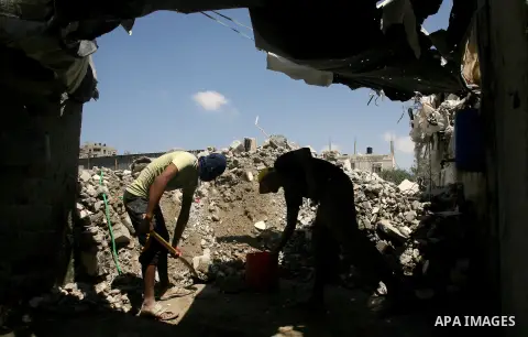 Palestinian laborers work on a crusher machine at a brick factory in Rafah in southern Gaza Strip, Aug 31, 2013. Palestinians re-use old bricks in construction after the Egyptian army started to knock down Gaza smuggling...