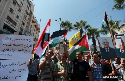 Palestinian protesters hold a flags and poster during a demonstration in solidarity with people of the Syrian and Egyptian, in the West Bank City of Ramallah Sep. 03, 2013. Photo by Issam Rimawi