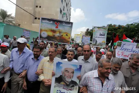 Palestinian Hamas supporters wave national flags while holding pictures of Sheik Raed Salah, the leader of the Islamic Movement in Jerusalem, during a protest to condemn the desecration of Al-Aqsa Mosque in Jerusalem by...