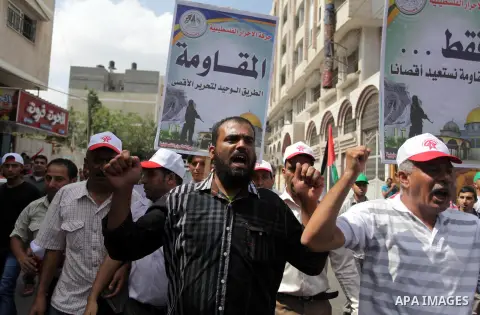 Palestinian Hamas supporters wave national flags while holding pictures of Sheik Raed Salah, the leader of the Islamic Movement in Jerusalem, during a protest to condemn the desecration of Al-Aqsa Mosque in Jerusalem by...