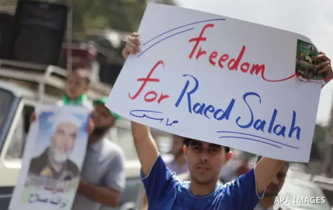 Palestinian Hamas supporters wave national flags while holding pictures of Sheik Raed Salah, the leader of the Islamic Movement in Jerusalem, during a protest to condemn the desecration of Al-Aqsa Mosque in Jerusalem by...
