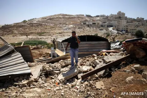 A Palestinian man walks on the debris of housing containers in the east Jerusalem village of al-Zaeem, Sept. 11, 2013. Israeli bulldozers demolished on Wednesday morning 20 housing containers belonging to the al-Saidi fa...