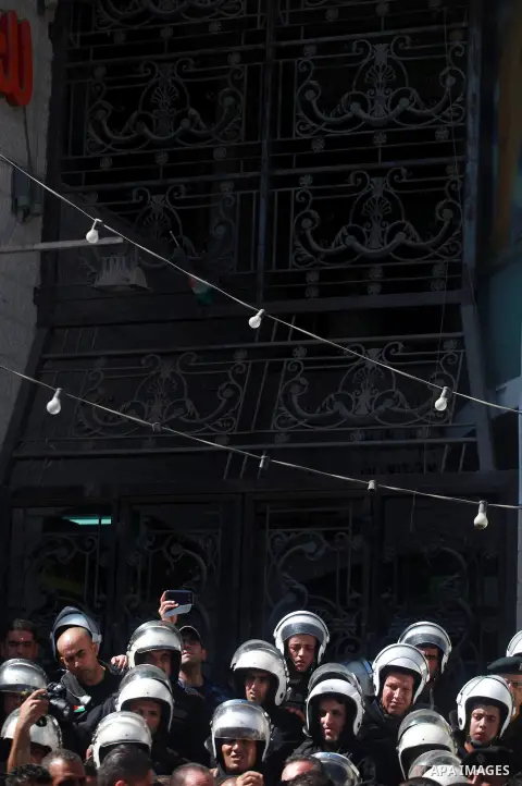 Palestinian policemen stand guard outside the Qatar-based Al-Jazeera Arabic news channel offices where members of the Fatah movement protest following the airing last night of a program they believe insulated the late Pa...
