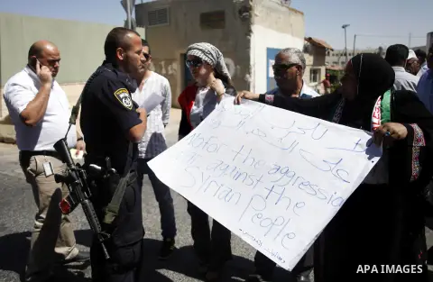 Palestinian protesters hold Syrian flags and placards as they take part in a demonstration against any US aggression against Syria held outside the former US Consulate in East Jerusalem, 11 September 2013. About two doze...