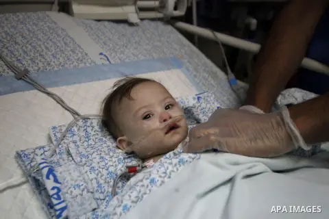 A Palestinian nurse stands next to Qamar Shehada, a 6 months Jordanian girl, as she laying on a hospital bed at the intensive care unit, in Jerusalem on Sept. 17, 2013. Israeli authorities prevented Shehada's family to e...