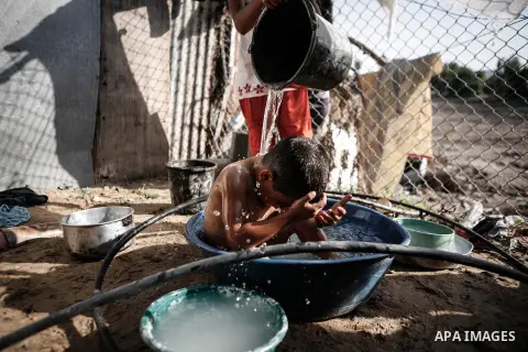 A Palestinian girl bathes her brother outside their family's home in a poverty-stricken quarter of al-Zaytoon in Gaza City on Sept. 17, 2013. Reports said that an increasing number of Gaza families are reportedly falling...
