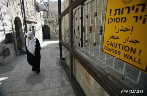 A Palestinian woman walks past a cracked building in Jerusalem's old City on Sept. 18, 2013. Israeli authorities issued evacuation orders to 20 Palestinian families in the al-Qarmi neighborhood of of Jerusalem's Old City...