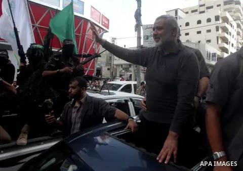 Palestinian Prime Minister in Gaza Strip, Ismail Haniya wave to militant members of the military Hamas wing Izz Ad-Dine Al-Qassam Brigades are seen during a march along the streets of Al Shatee refugee camp in Gaza City,...