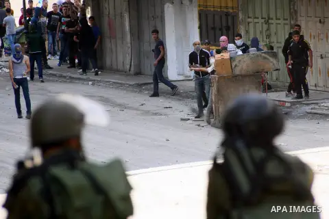 Palestinian youths throw stones at Israeli soldiers during clashes against the blocked roads in the West Bank city of Hebron, on Sep. 22, 2013. Israeli forces Sunday fired tear gas canisters and rubber-coated steel bulle...