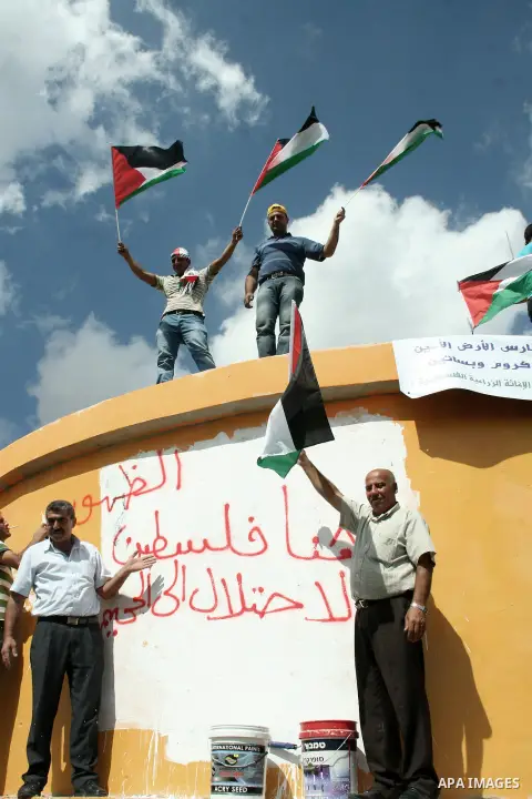 Palestinian farmers remove Hebrew slogans written by Israeli settlers on a water tank on their land, near the village of Burqa, north of Nablus, the West Bank, 03 October 2013. According to Israeli human rights group Yes...