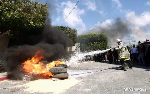 A member of Palestinian firefighters sprays water on burning tyres during a emergency evacuation drill of Al Aqsa hospital in Deir al-Balah town, central Gaza Strip, 03 October 2013. Photo by Mahmoud Hamda