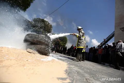 A member of Palestinian firefighters sprays water on burning tyres during a emergency evacuation drill of Al Aqsa hospital in Deir al-Balah town, central Gaza Strip, 03 October 2013. Photo by Mahmoud Hamda