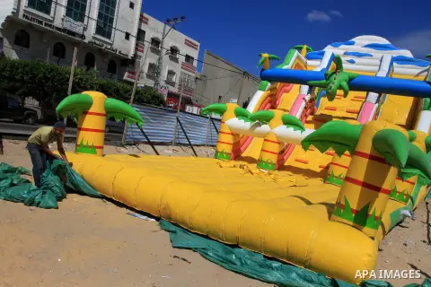 A Palestinian worker prepares the children games during a preparing to the celebration of Eid al-Adha festival at a market in Gaza city, on Oct. 05, 2013. Muslims around the world prepare to celebrate Eid Al-Adha, which...