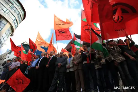 Palestinians from different political movements hold up their flags during a protest in the West Bank city of Ramallah, on October 6, 2013, calling on Palestinian president Mahmud Abbas to withdraw from peace negotiation...