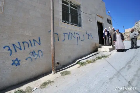 Palestinians walk past graffiti reading in Hebrew, "Mohammed (prophet) is a pig" sprayed on a mosque in the West Bank village of Beit Iksa on October 7, 2013. The Palestinians must "recognise Israel as the state of the J...