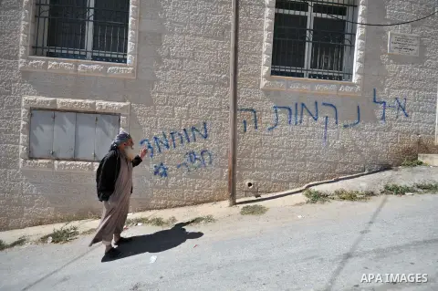 A Palestinian man points at a graffiti reading in Hebrew, "Mohammed (prophet) is a pig" sprayed on a mosque in the West Bank village of Beit Iksa on October 7, 2013. The Palestinians must "recognise Israel as the state o...