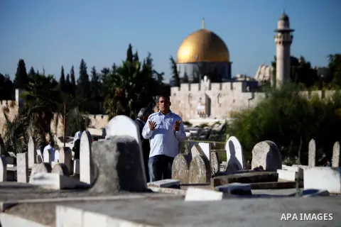 A Palestinian man prays at the grave of a relative in a cemetery near the Al-Aqsa Mosque compound, Islam's third holiest shrine, in Jerusalem s old city following morning prayers on the Muslim holiday of Eid al-Adha or "...
