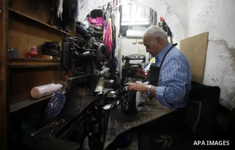 A Palestinian tailor sews at his workshop in Jerusalem's Old City on October 21, 2013. Photo by Saeed Qaq
