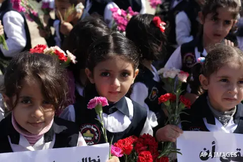 Palestinian school children throw flowers into the Seaport of Gaza City October 23, 2013, to remember the Palestinian migrants who died after their boat sank while fleeing Syria to Italy. A boat capsized 60 miles south o...