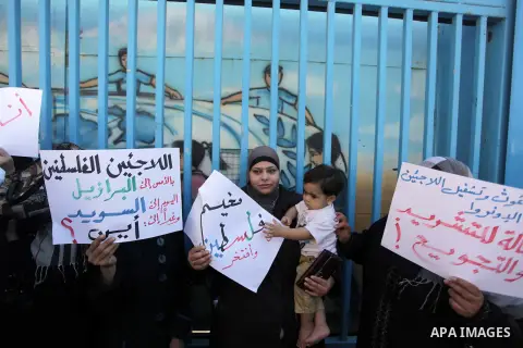Palestinian families who fled Syria hold placards during a protest in front of the headquarters of the United Nations Relief and Works Agency (UNRWA) to demand assistance and work on October 28, 2013 in Gaza city. Photo...