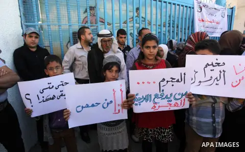 Palestinian families who fled Syria hold placards during a protest in front of the headquarters of the United Nations Relief and Works Agency (UNRWA) to demand assistance and work on October 28, 2013 in Gaza city. Photo...